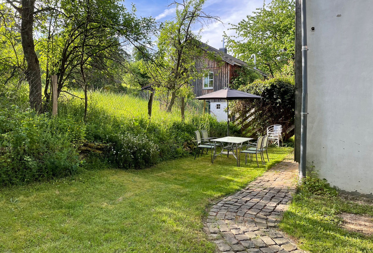 Weg hinters Haus zur Sitzecke mit Sonnenschirm